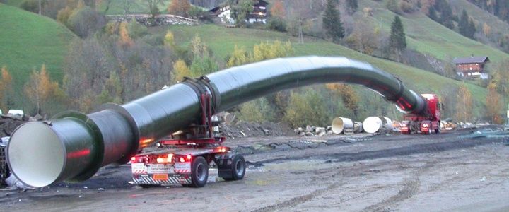 Roter LKW für Sondertransporte in Tirol transportiert langes Rohr